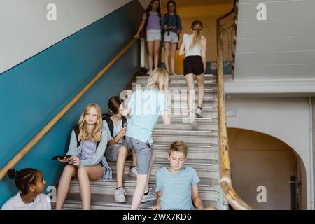 Studenti di sesso maschile e femminile sulle scale durante la pausa scolastica Foto Stock