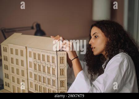 Professionista del design femminile che prepara il modello di costruzione mentre lavora in ufficio Foto Stock
