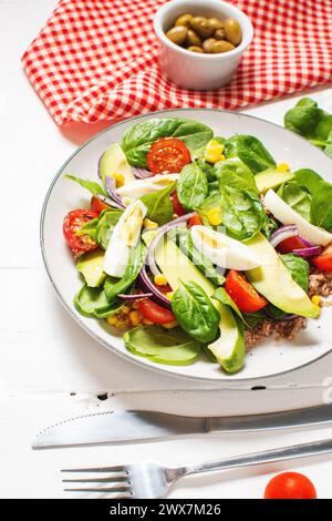 Insalata di tonno: Tonno, avocado, uova sode, pomodori ciliegini, lattuga e cipolla su tavola di legno. Cibo sano Foto Stock