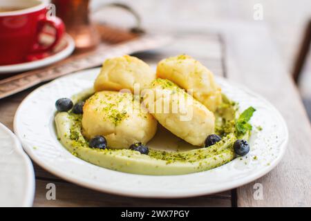 Syrniki tradizionale frittelle di formaggio russo con mirtilli e panna di pistacchio Foto Stock