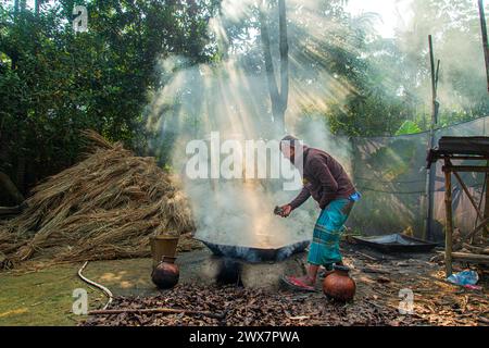 Un vecchio fa melassa bollendo il succo di dattero raccolto da palme da dattero in un grande vaso. In inverno, la linfa viene raccolta da palme e. Foto Stock