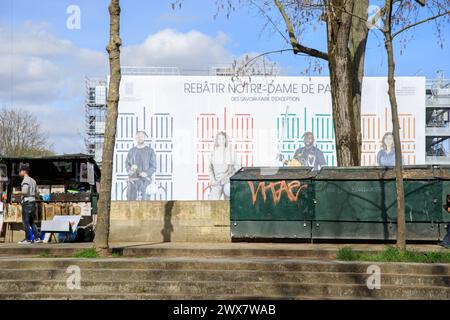 Francia, regione Ile-de-France, Paris rive Gauche, 5° arrondissement, quai de Montebello, scatole di bouquinistes (scatole di libri di seconda mano) e teloni con la scritta "rebâtir Notre-Dame" (ricostruire Notre-Dame de Paris) 19 marzo 2024 Foto Stock