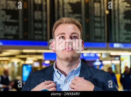 28 marzo 2024, Assia, Francoforte sul meno: Marvin Reschinsky, segretario sindacale Verdi e negoziatore capo per il lato dei dipendenti, si trova di fronte al grande tabellone per le partenze al Terminal 1 dell'aeroporto. Il negoziatore Verdi dell'aeroporto Reno-meno ha rilasciato una dichiarazione sulla mediazione riuscita nella controversia salariale tra i servizi terrestri della Lufthansa e la Lufthansa. Foto: Andreas Arnold/dpa Foto Stock