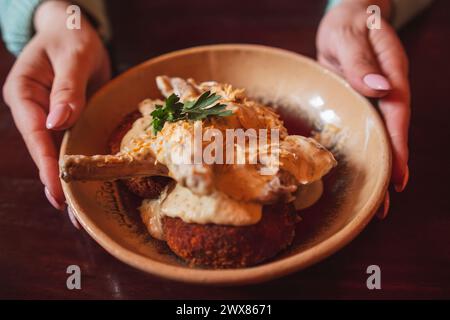 Una succulenta spalla di coniglio guarnita con erbe e salsa cremosa. Foto Stock