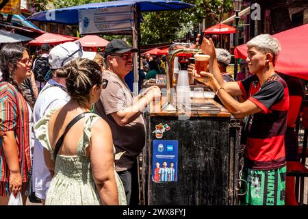 A Young Man serve birra ai turisti nel quartiere la Boca di Buenos Aires, Argentina. Foto Stock