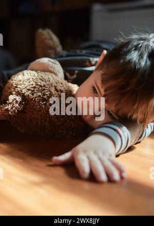 bambino che abbraccia un orso giocattolo nella stanza dei bambini durante il pisolino Foto Stock