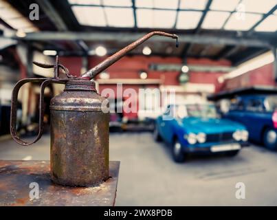 Grungy Rusty lattina con Un gocciolamento d'olio in un negozio di riparazione di automobili con auto d'epoca e spazio copie Foto Stock