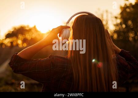 Donna con le cuffie che si gode il tramonto. Foto Stock