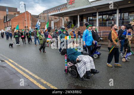 Lady in sedia a rotelle si unisce alla processione di Warrington St Patrick's Day mentre passa davanti alla stazione ferroviaria centrale Foto Stock