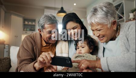 Selfie, donna e genitori anziani con bambini che si legano insieme su un divano per rilassarsi a casa. Felice, sorridente e donna con cui scattare una foto Foto Stock