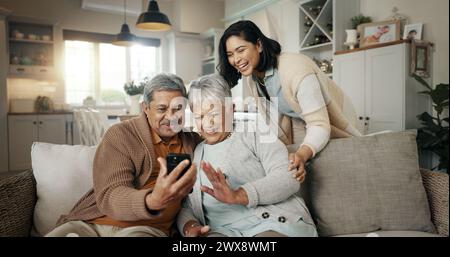 Videochiamata, soggiorno e donna con genitori anziani su un divano che si rilassa e parla al telefono. Sorriso, legame e persona femminile con anziani Foto Stock