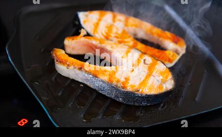 Nella padella nera quadrata sono presenti due pezzi di bistecche di salmone alla griglia Foto Stock