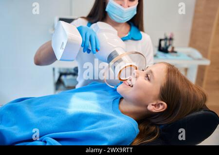 Il medico tiene in mano una lampada fotopolimerica dentale Foto Stock