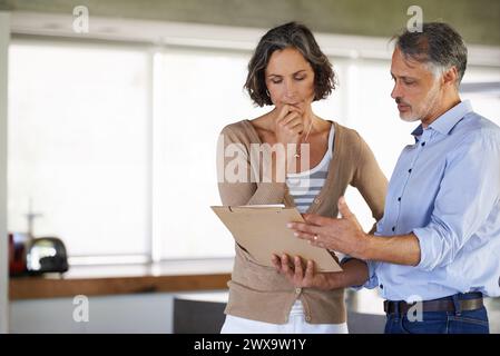 Serio, coppia e documenti in casa per bollette, budget o risoluzione di problemi per il debito. Lettera, uomo e donna maturi con le tasse, fallimento e lettura male Foto Stock