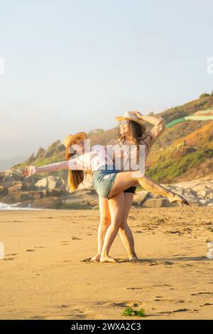 Uno scatto verticale di due giovani donne ispaniche che posano su una spiaggia soleggiata Foto Stock