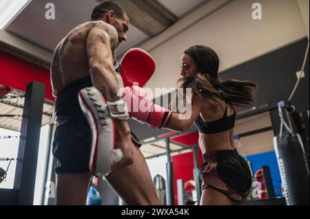 Artista marziale femminile che gioca a sparring con allenatore in palestra Foto Stock