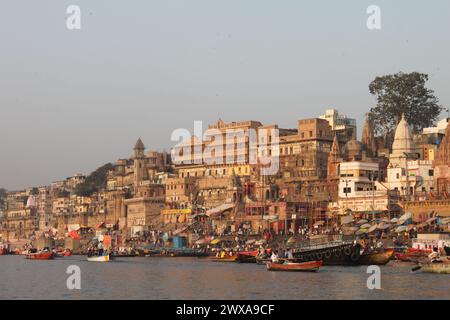 Varanasi, India - 13 marzo 2019: Vita quotidiana al Munshi Ghat sulle rive del fiume santo Gange a Varanasi all'alba. Barche colorate, vecchi edifici Foto Stock