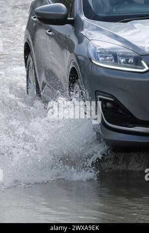 Lacock, Wiltshire, Regno Unito. 29 marzo 2024. Il fiume Avon a Lacock ha fatto scoppiare le sue sponde e ha inondato la strada dentro e fuori il villaggio. Il Consiglio è di non guidare attraverso l'acqua piena, ma la strada è percorribile se si vuole fare un tuffo. Crediti: JMF News/Alamy Live News Foto Stock