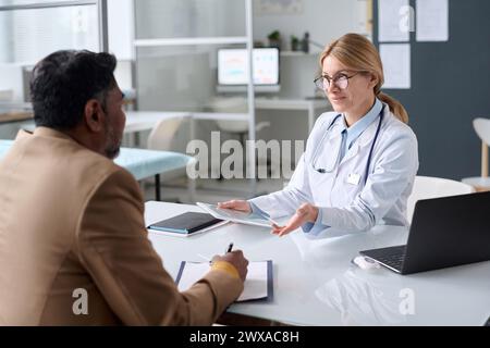 Ritratto di medico donna maturo consulenza uomo indiano in clinica medica e sorridente amichevole Foto Stock