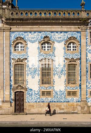 La donna passa davanti alla facciata della chiesa di Igreja do Carmo, adornata con intricate piastrelle blu e bianche, Porto, Portogallo Foto Stock