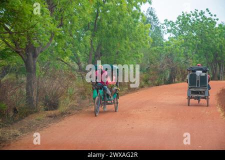 Antsirabe, Madagascar. 18.10. 2023. Il pedicab in Madagascar trasporta i passeggeri lungo una strada polverosa. Trasporto tradizionale per questa zona Foto Stock