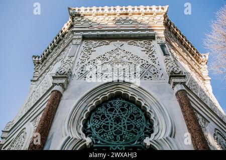 Vista ad angolo basso di una torre storica ornata con intricate incisioni e una finestra decorativa, adagiata su un cielo limpido Foto Stock
