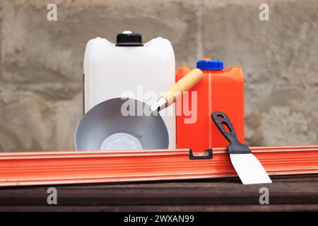 Mestolo per intonaco o da costruzione, una spatola, una livella da costruzione e un contenitore per primer. Ristrutturazione di case di campagna, costruzione. Composizione e. Foto Stock