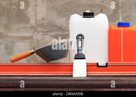 Mestolo per intonaco o da costruzione, una spatola, una livella da costruzione e un contenitore per primer. Ristrutturazione di case di campagna, costruzione. Composizione e. Foto Stock