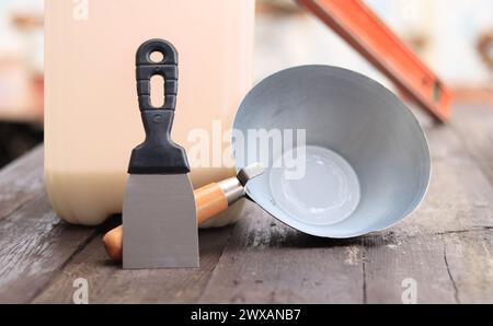 Mestolo per intonaco o da costruzione, una spatola, una livella da costruzione e un contenitore per primer. Ristrutturazione di case di campagna, costruzione. Composizione e. Foto Stock