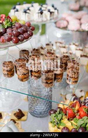 Un tavolo in legno mostra una varietà di dessert e cupcake in avvolgimenti colorati e gelate, creando un'allettante e deliziosa diffusione. Foto Stock