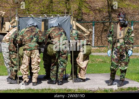 Un gruppo di soldati è in piedi intorno a una tenda, con uno di loro che indossa una maschera antigas. I soldati sembrano lavorare insieme, forse in missione Foto Stock