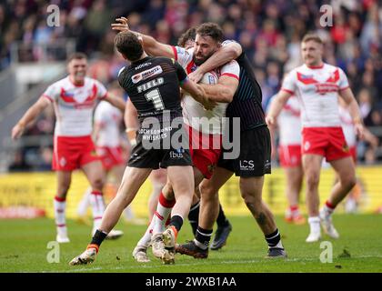 Alex Walmsley dei St Helens viene placcato da Jai Field dei Wigan Warriors e Harry Smith durante il Betfred Super League match al Totally Wicked Stadium di St Helens. Data foto: Venerdì 29 marzo 2024. Foto Stock