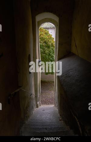 Stretto vecchio passaggio in Europa. Una porta su un vicolo alla fine di uno stretto passaggio in una storica cittadina medievale europea. Foto Stock