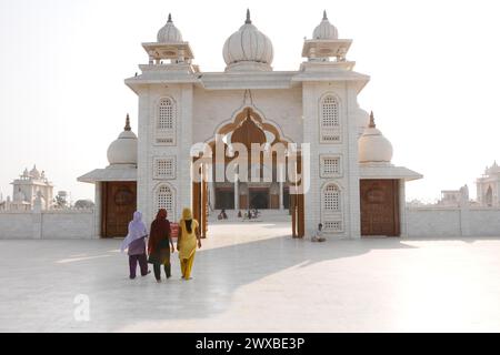 Tre persone in abito tradizionale camminano verso un tempio alla luce del sole diffusa, vicino a Jaipur, Rajasthan, India Foto Stock