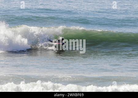 Un surfista in abito nero cavalca un'onda nel mare, nel nord del Portogallo, vicino a Mindelo, in Portogallo Foto Stock