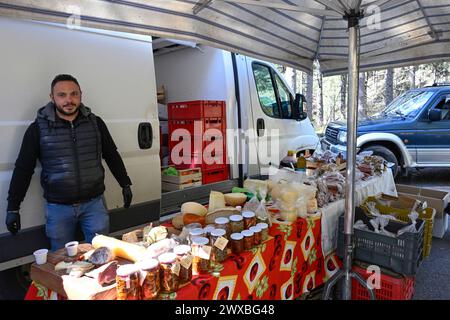 Lorica, Italia - marzo 2024: Venditore dietro banco con carne e salsiccia al mercato locale. Bancarelle di mercato con prodotti tradizionali italiani Foto Stock