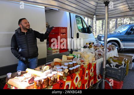 Lorica, Italia - marzo 2024: Venditore dietro banco con carne e salsiccia al mercato locale. Bancarelle di mercato con prodotti tradizionali italiani Foto Stock