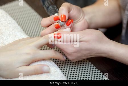 Il maestro della manicure seziona e attacca una forma di chiodo durante la procedura di estensione delle unghie con gel nel salone di bellezza. Assistenza professionale Foto Stock