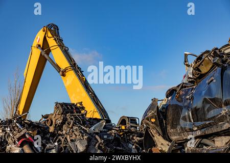 Colpo ritagliato di una gru gialla in un cantiere. Macchine impilate e motore in un deposito nel villaggio di Lisse, nei Paesi Bassi, nell'Olanda meridionale. Su un blu Foto Stock