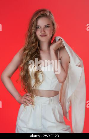 Donna che trasuda sensualità, vestita con un top in corsetto a coste con una giacca drappeggiata sulla spalla. Il modello ha lunghi capelli ondulati, con un look elegante Foto Stock