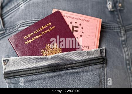 Primo piano su un passaporto francese e una patente di guida nella tasca posteriore di jean. Foto Stock