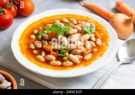 Fagioli tradizionali turchi con olio d'oliva, cipolla e pasta di pomodoro in un piatto di ceramica su fondo rustico Foto Stock