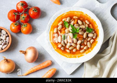 Fagioli tradizionali turchi con olio d'oliva, cipolla e pasta di pomodoro in un piatto di ceramica su fondo rustico Foto Stock