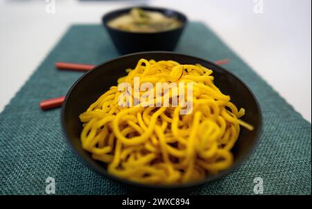 Yakisoba nel cestino da pranzo e nel piatto con Chique Hashi Foto Stock