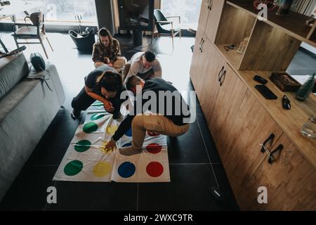 Amici che giocano a Twister in un ambiente accogliente, divertente e divertente Foto Stock