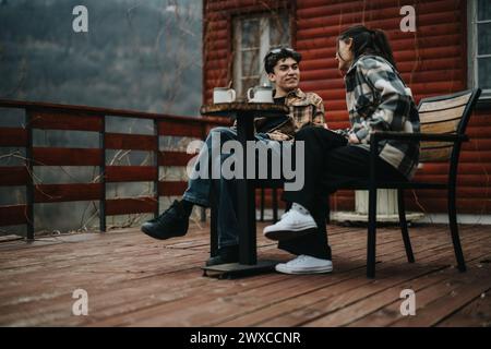 Una giovane coppia si diverte a conversare con un caffè in una veranda. Foto Stock