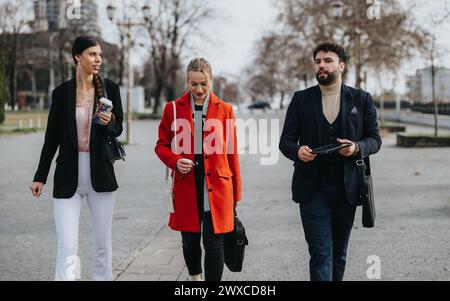 Tre professionisti che camminano all'aperto in conversazioni informali Foto Stock