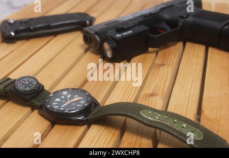 Orologio militare con bussola e pistola sul tavolo Foto Stock