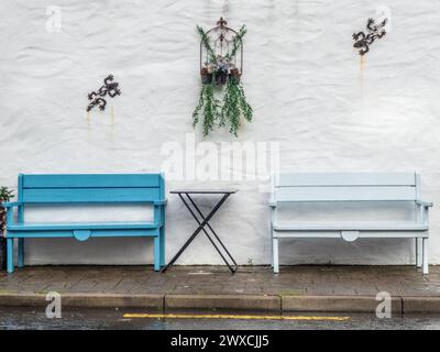 due panchine davanti a un muro bianco ti invitano a fare una pausa. Foto Stock