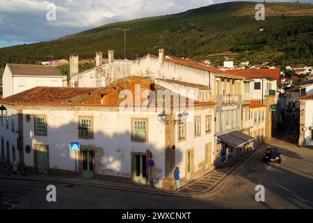 Case a schiera fatiscenti all'angolo di strada acciottolata alla luce del tramonto, campagna collinare sullo sfondo, Torre de Moncorvo, Portogallo Foto Stock